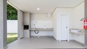 A clean, modern outdoor kitchen with a built-in oven, a sink, and a fire extinguisher. - Modern Apartment in a Condo With Pool Rnm0015 (Porto Seguro)