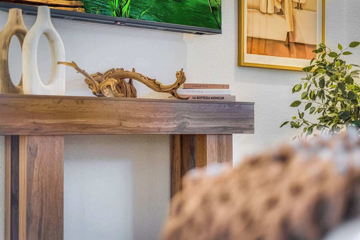 Una estantería de madera con adornos, un televisor y un cuadro en la pared.