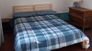 Una stanza con un letto, una testiera in legno, un comodino con una lampada e una lampada a sospensione.