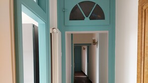 Un corridoio con pareti color acquamarina, pavimento in legno e una porta con maniglia in ottone.
