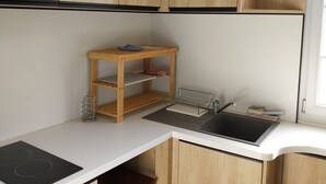 Una cucina compatta con mobili in legno, un lavello, un piccolo tavolo di legno e un piano cottura integrato.
