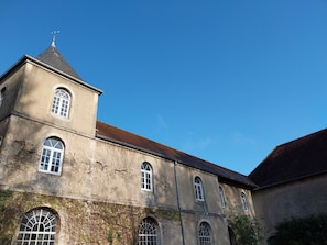 A building with a tower, arched windows, and a red roof. - The Pavilion: An Unconventional Apartment (Saint-Lothain)