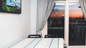 Una habitación con una cama, dos sillas, un ventanal con cortinas y un cuadro en la pared.