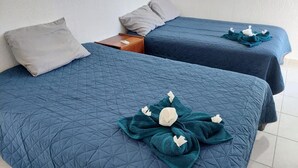 Twee bedden met blauwe dekens en handdoeken.