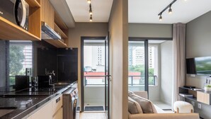 A modern kitchen with a built-in oven, a dining area with a sofa, and a balcony with a view of buildings. - Condo. w/ Rooftop Pool, 270m fr/ the Metro, Jardins - Gabs (São Paulo)