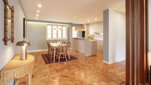 Cocina moderna con una isla central, mesa de comedor de madera con sillas y un ventanal grande.