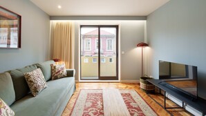 Una sala de estar con un sofá, un televisor, una puerta corrediza de vidrio y una alfombra estampada.