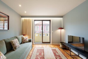 A living room with a sofa, a TV, a sliding glass door, and a patterned rug. - VIVA Serpa Pinto Serviced Apartment 1D (Porto)