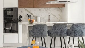 A modern kitchen with white cabinets, a marble backsplash, and a built-in oven. - Quinta Atia – Private Pool Hideaway (Caldas da Rainha)
