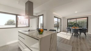 A modern kitchen with a marble countertop, a built-in oven, and a window overlooking the city. - Quinta Atia – Private Pool Hideaway (Caldas da Rainha)