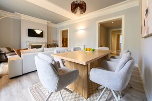 Un espace repas moderne avec une table en bois, des chaises à revêtement gris et un panier de fruits.