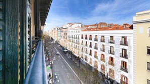 Eine Stadtstraße mit Gebäuden, blauem Himmel und einem Fußweg.