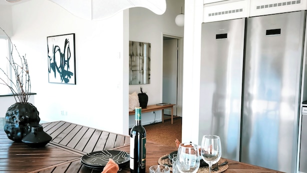 Un espace de salle à manger moderne avec une table en bois, une bouteille de vin et des verres.