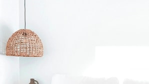 Une chambre à coucher avec un lit, un luminaire suspendu et une table de chevet sur laquelle se trouve un vase.