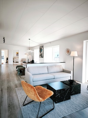 Un salon moderne avec un canapé, un fauteuil, une table basse et une lampe.