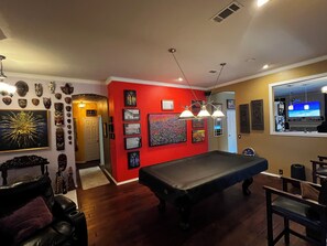Une pièce avec une table de billard, un mur d’accent rouge et divers éléments de décoration murale.