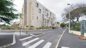 Ein mehrstöckiges Gebäude im modernen Stil, eine Fußgängerzone und eine Straße mit einem Stoppschild.