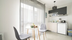 Una cucina moderna con zona pranzo, che include un tavolo bianco con sedie, un forno a microonde e un lavello.