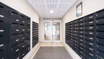 A hallway with rows of black mailboxes, a tiled floor, and a double door at the end.