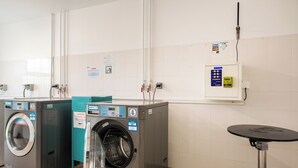 A laundry area with two washing machines, a small table, and a payment terminal. - 402 - L'Herblinois - Wifi - Proche tram (Saint-Herblain)