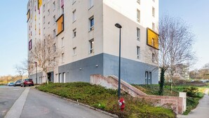 A multi-story building with a flat facade, a fire hydrant, and a parking area with cars. - 402 - L'Herblinois - Wifi - Proche tram (Saint-Herblain)
