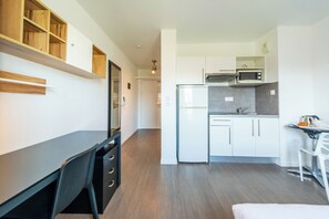 A modern kitchen with white cabinets, a microwave, and a refrigerator. There is a dining area with a table and chairs. - 402 - L'Herblinois - Wifi - Proche tram (Saint-Herblain)