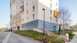 En bygning med flere etager, flad facade, brandhane og en parkeringsplads med biler.