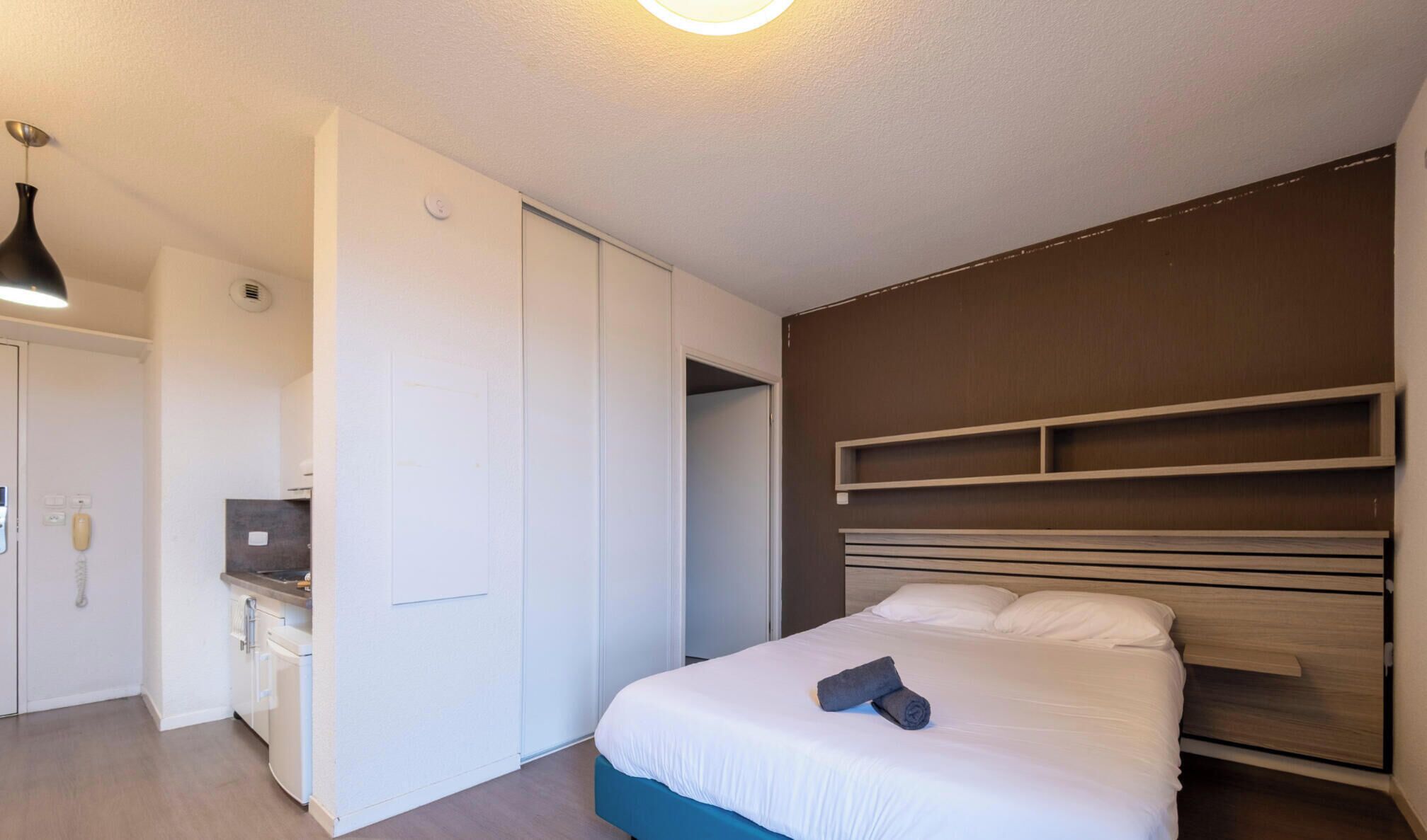 Un dormitorio con cama, escritorio y armario.