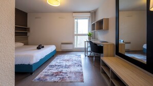 Una habitación de hotel moderna con cama, escritorio, silla y un espejo grande.
