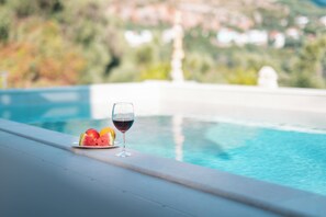 Ein Poolbereich mit einem Glas Rotwein und Wassermelonenschnitten auf einem Teller.