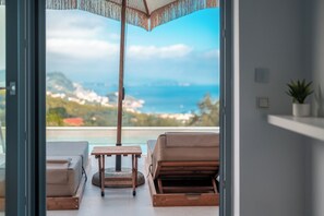 Ein Balkon mit Blick aufs Meer, einem Holztisch und zwei Liegestühlen.