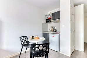 Eine kleine Küche mit Mikrowelle, Kühlschrank und einer Essecke für zwei Personen mit rundem Tisch.