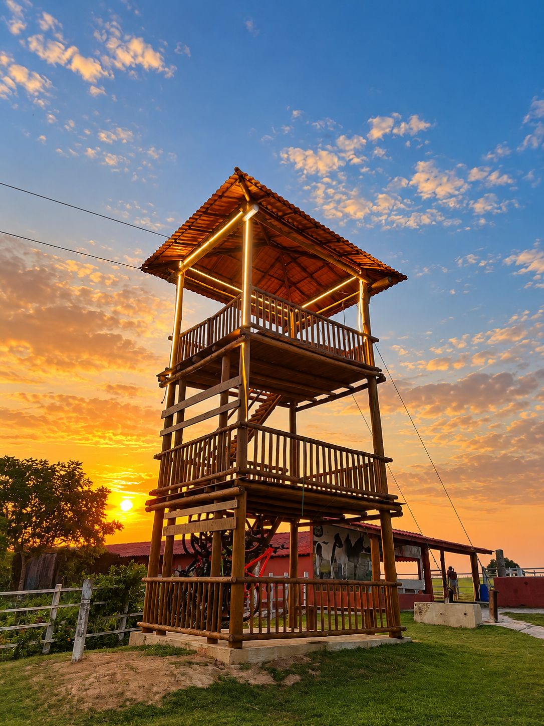 Una estructura de madera de varios niveles con un balcón, frente a un cielo al atardecer.