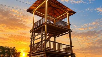 Una estructura de madera de varios niveles con un balcón, frente a un cielo al atardecer.