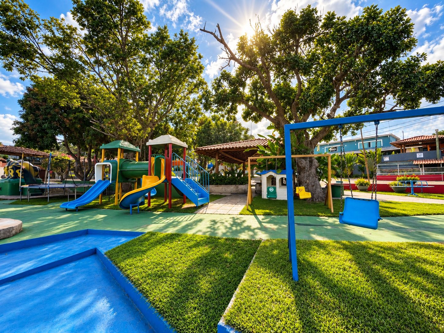 A playground with slides and swings, surrounded by trees and a clear sky.