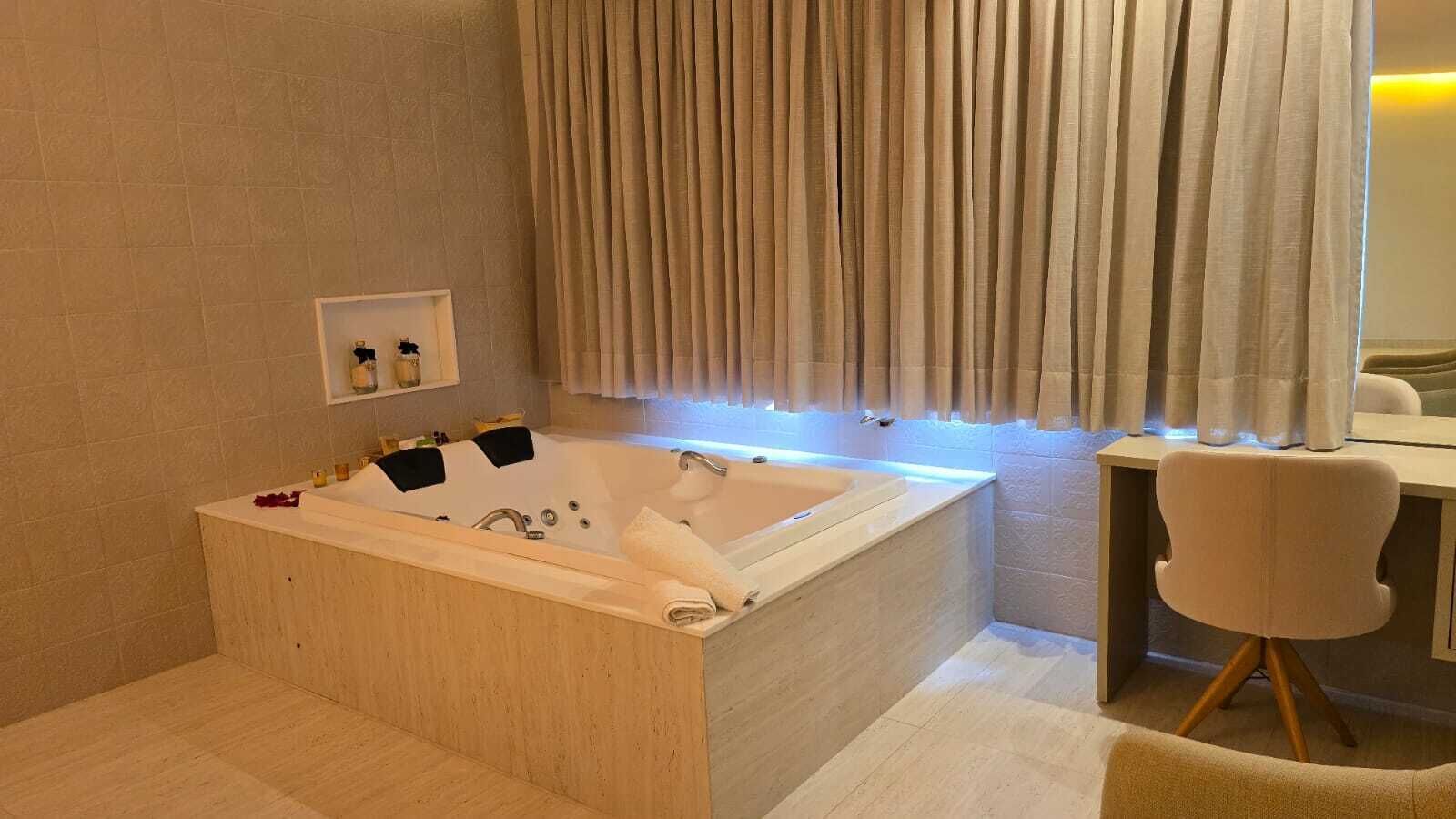 Uma casa de banho moderna com uma banheira independente, um lavatório com espelho e uma cadeira.