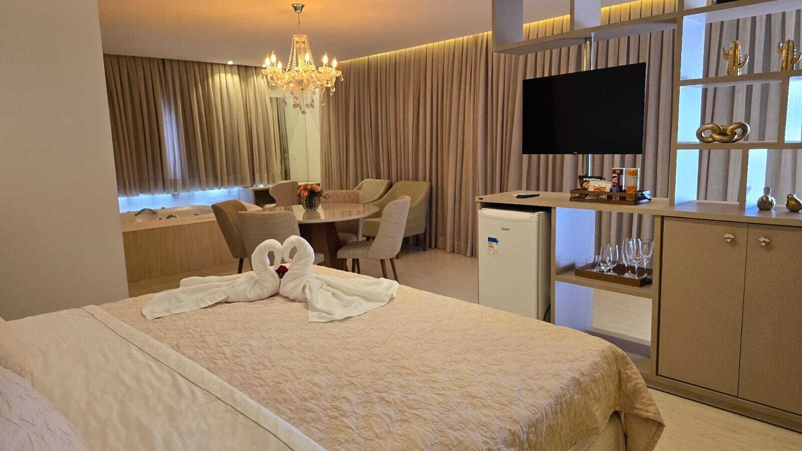 A hotel room with a bed, a desk, a television, and a minibar.