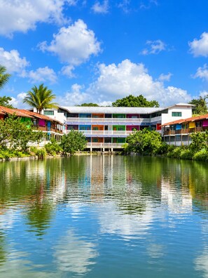 A multi-story hotel with balconies, a pool, and a tropical garden. - Amoras Hotel Fazenda (Conceição do Almeida)