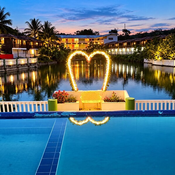 A swimming pool with a heart-shaped light decoration, surrounded by a white fence and a bench. - Amoras Hotel Fazenda (Conceição do Almeida)