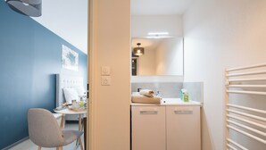 Een kleine badkamer met een wastafel, spiegel en handdoekhouder.