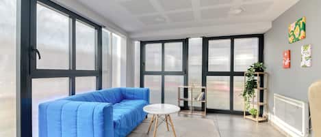 A modern living room with a blue sofa, a round table, and a radiator.