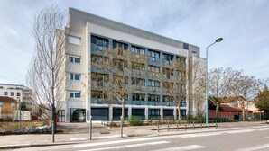 Ein modernes Gebäude mit mehreren Stockwerken, großen Fenstern und einem Flachdach.