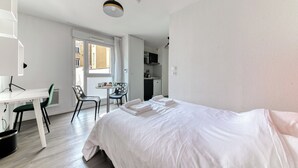Ein Hotelzimmer mit Bett, Schreibtisch, Stuhl und einer Küchenzeile.
