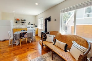 A cozy kitchen with a dining table, a sofa, and a large window.