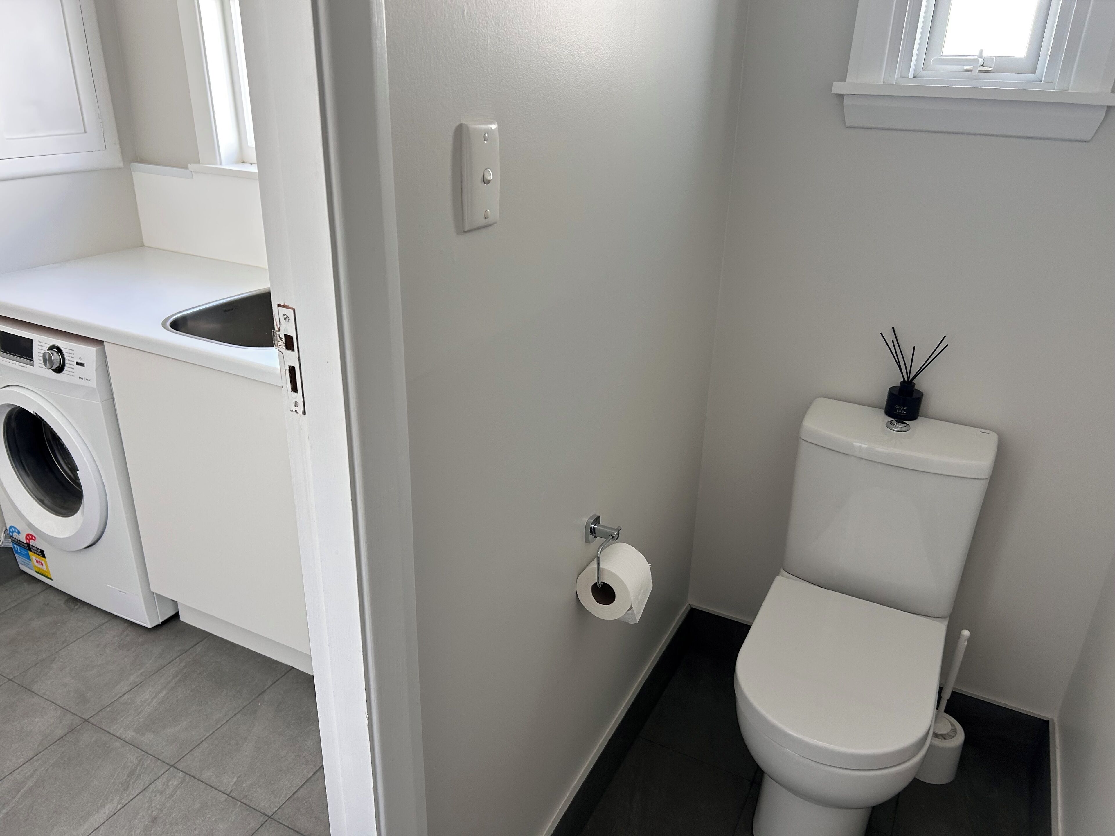 Een badkamer met een toilet, een wastafel en een wasmachine.