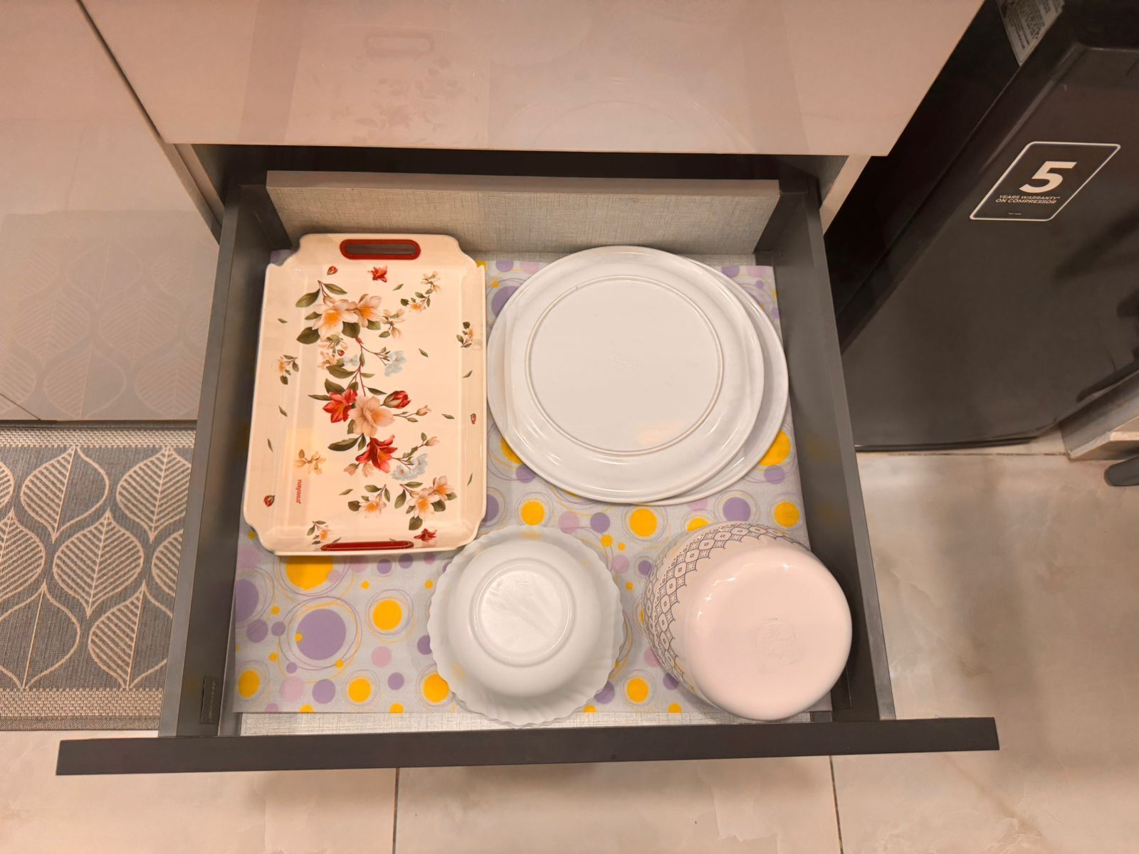 A drawer with a floral tray, two white plates, and a white bowl.
