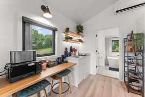 Een compacte keuken met een ingebouwde magnetron, een koffiehoek en uitzicht op de omgeving.