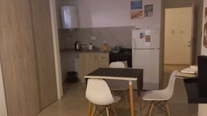 Ett litet kök med ett bord och stolar, ett kylskåp och en mikrovågsugn.