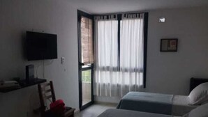Ett hotellrum med två sängar, en tv, ett skrivbord och en stol.