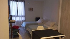 Ett rum med en säng, ett skrivbord och ett matbord med stolar.